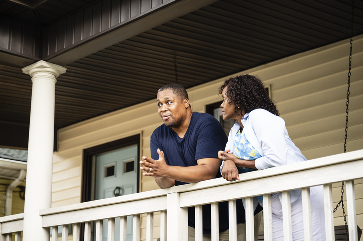 A couple in a serious conversation on a porch.